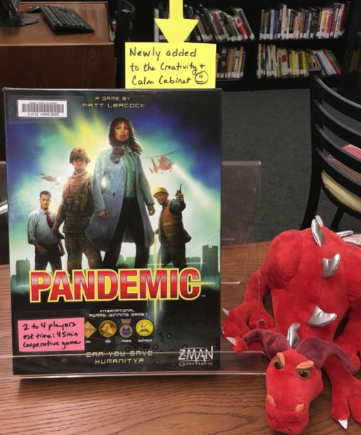 image of the Pandemic board game with a red stuffed dragon beside it